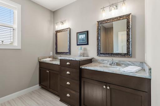 The primary ensuite bathroom includes a double sink with leathered marble countertops.