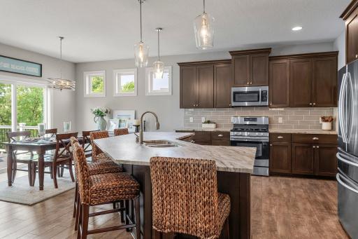 The kitchen features a gorgeous angled island, elegant leathered marble countertops and stainless steel appliances.