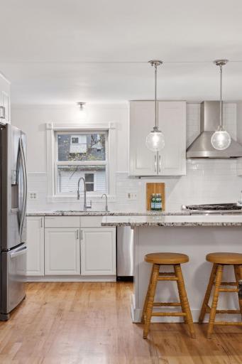 . The eat-in kitchen features granite countertops, center island, stainless steel appliances, and a large window that casts natural light throughout the space.