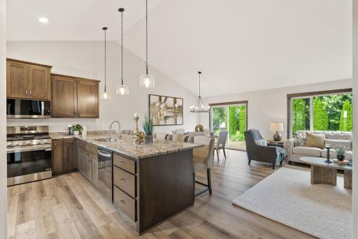 A view from the foyer looking into the dining room and great room. High volume vaulted ceilings. LVP flooring throughout the main level.