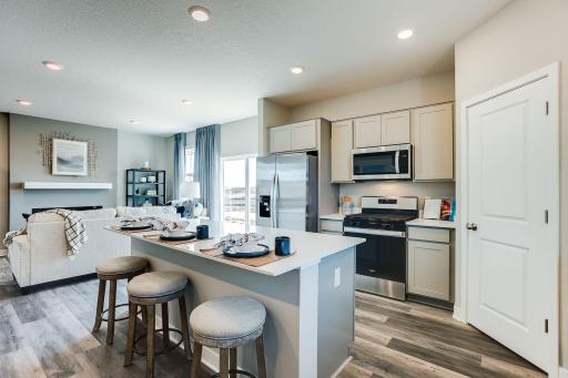Stunning AND functional all in one, as the kitchen space features a pantry closet for help with storage - and an oversized island coated in Quartz countertops with an overhang for seating!