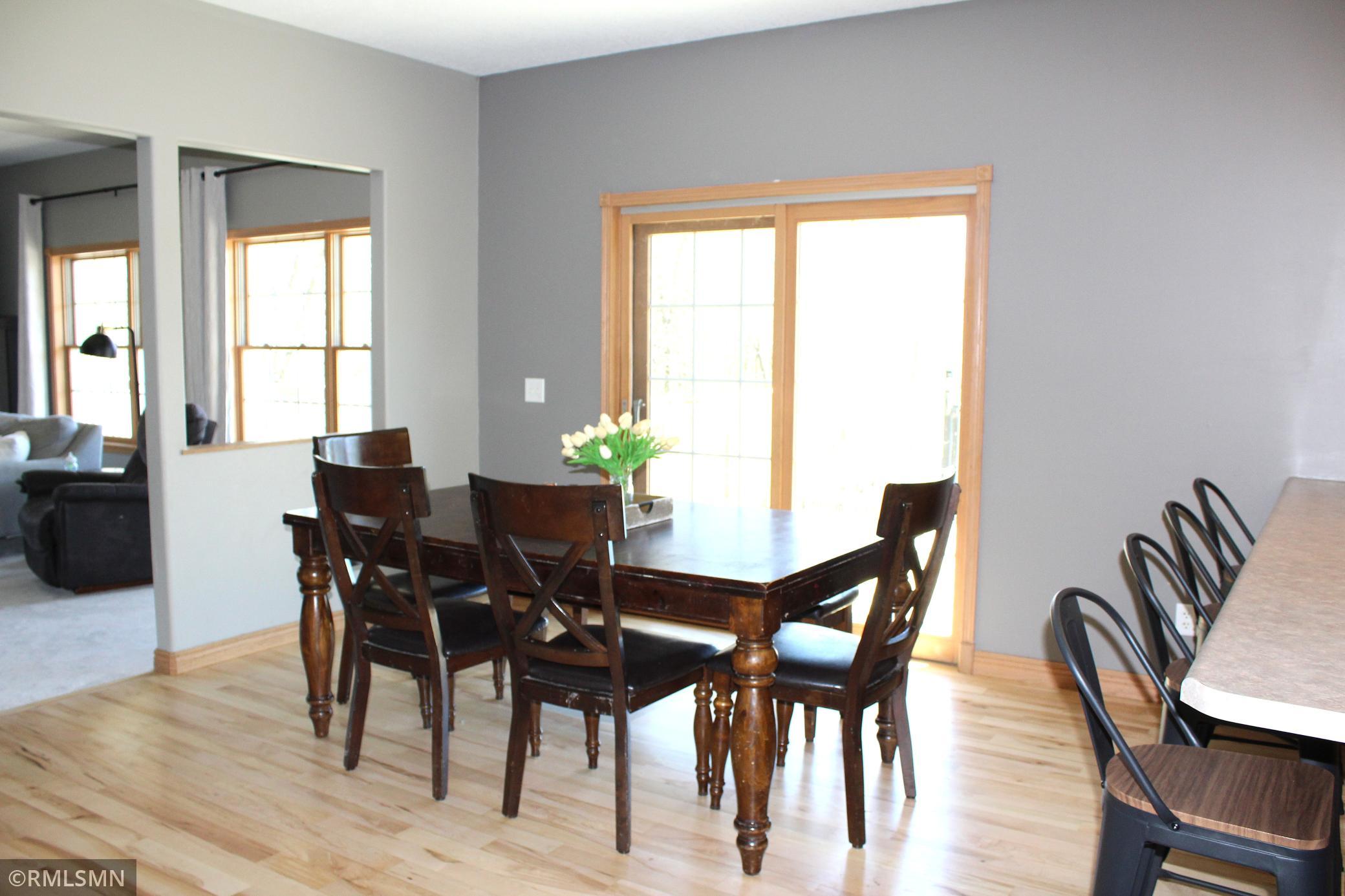 The dining room is nestled between the living room and kitchen, and has a sliding door that leads to the covered back porch and the deck.