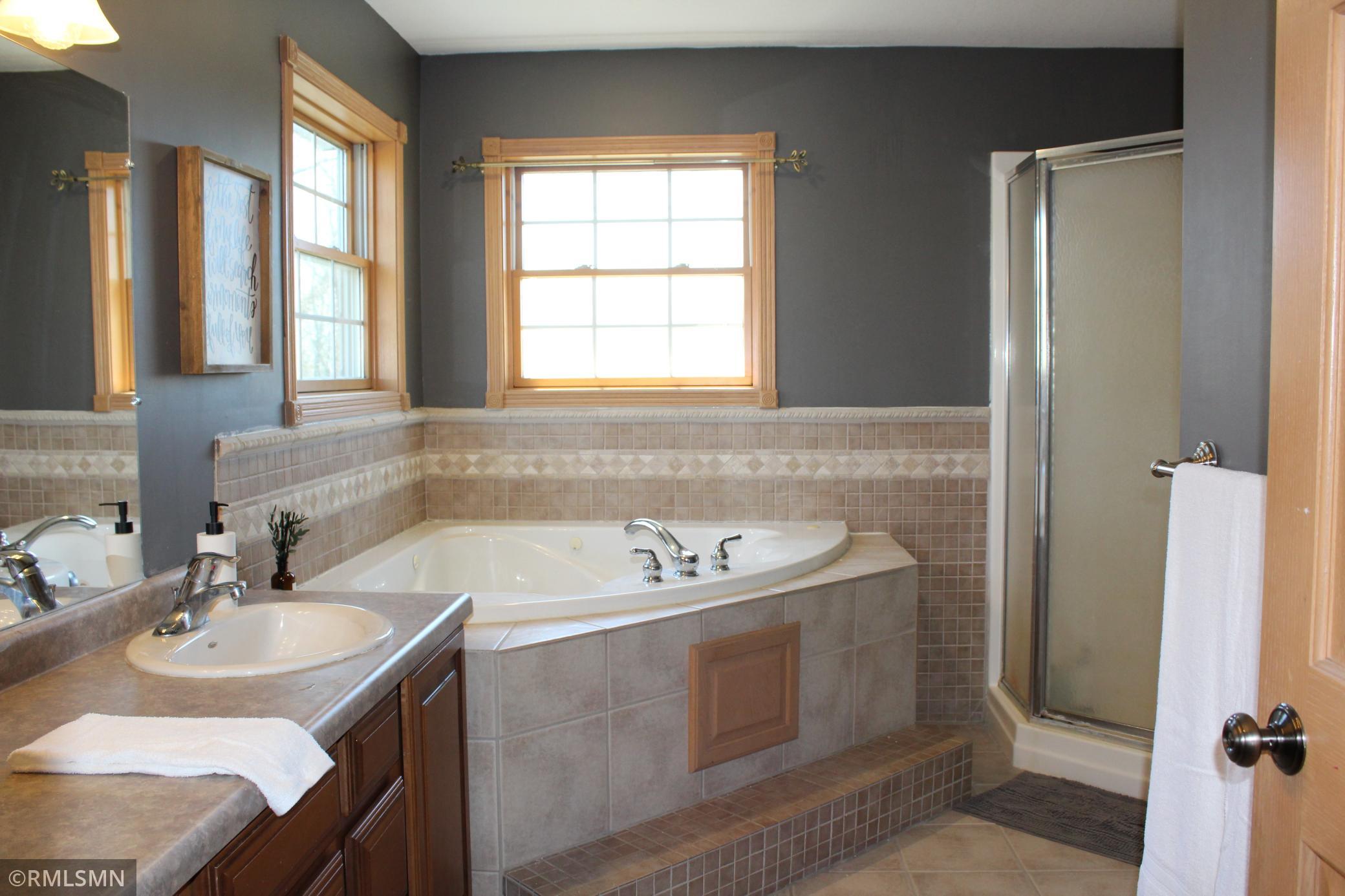 The spacious primary bathroom has double vanity sinks, a tub, shower, and a separate toilet area.