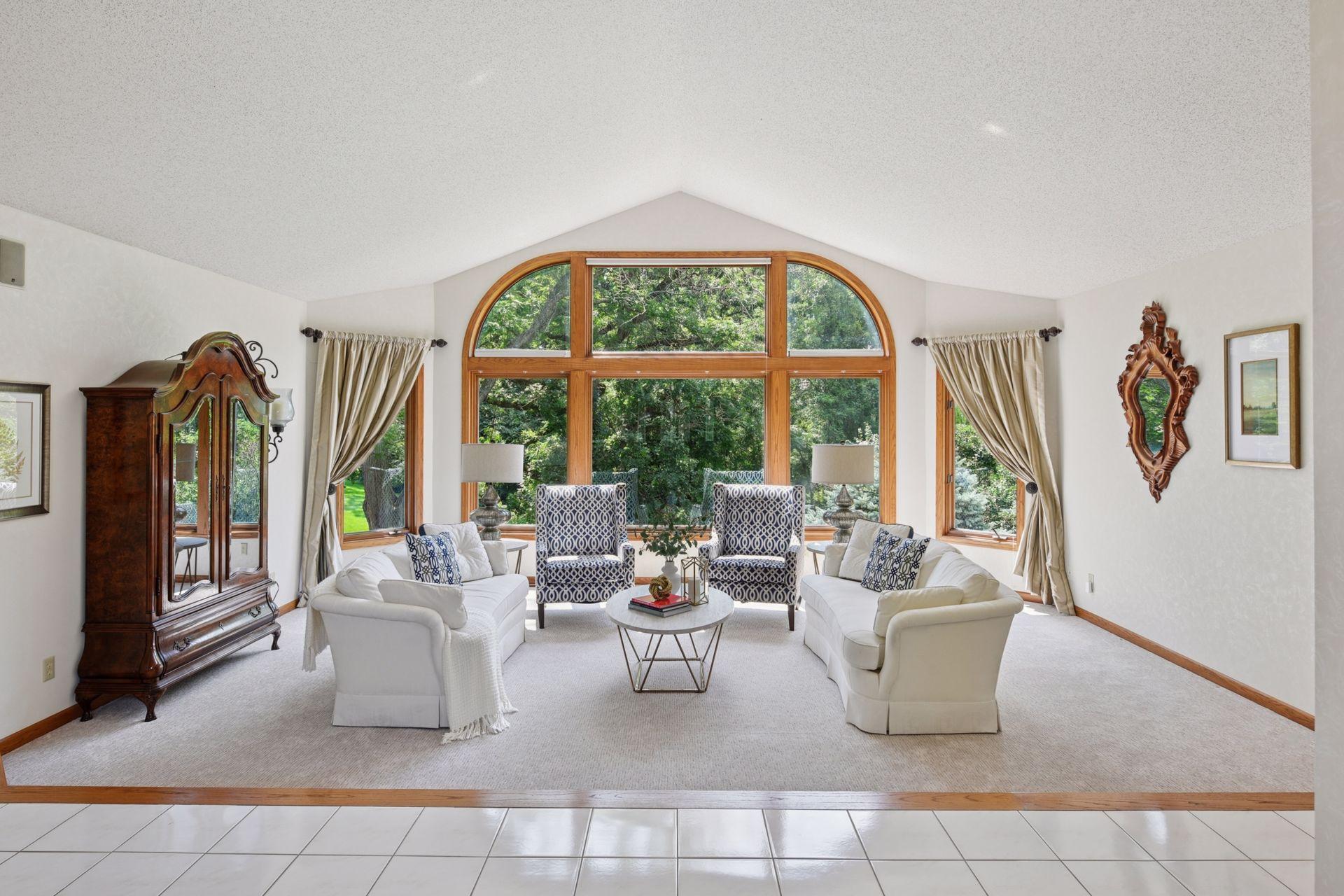The floor to ceiling window frames the outside like a piece of art for this formal living room space