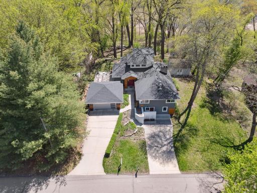 Modern curb appeal with sleek lines and updated exterior finishes. Spacious driveway and inviting double entry framed by mature trees. New roof in 2023!