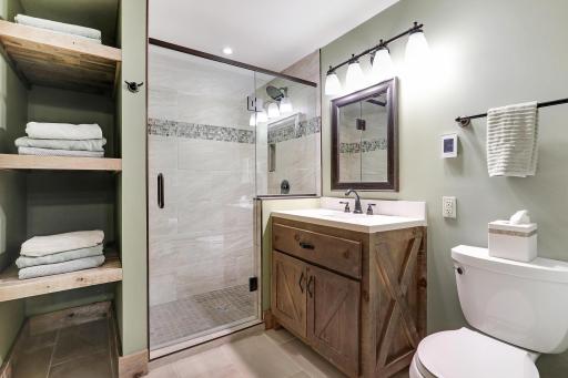 Beautiful lower level 3/4 bath with tile shower, wood vanity and built in storage.