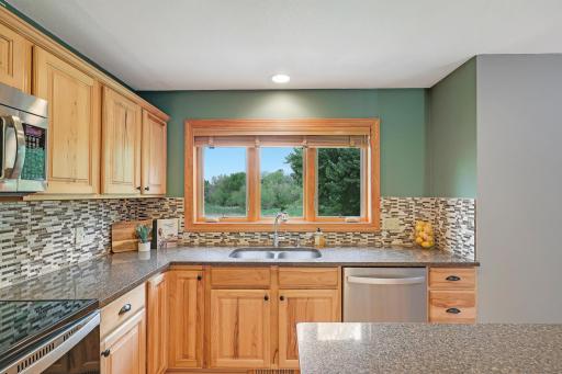 Spacious & open kitchen with large kitchen window, tile backsplash, quartz countertops, large central island and stainless steel appliances.