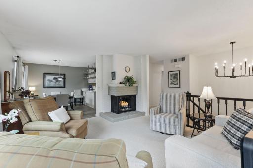Spacious and open layout from the living room with views into the kitchen and dining areasâfeaturing a cozy gas fireplace as a focal point.