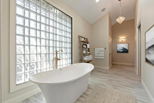 Primary bathroom suite with soaking tub and stunning glass block wall.