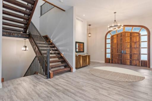 Grand entryway with oak staircase and custom double doors.