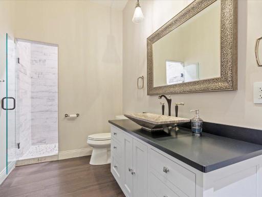 En suite bath featuring a walk-in shower, vessel sink, and rich finishes for a spa-like feel.