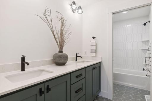 Two of the junior bedrooms share a full Jack and Jill bath with a comfort-height double vanity and a tiled tub/shower surroundâideal for busy mornings.