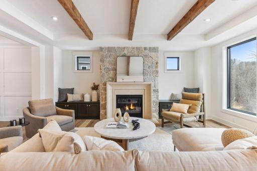 The Family Room features rustic ceiling beams, expansive windows, and a stone fireplace that anchors the room with texture and warmth.