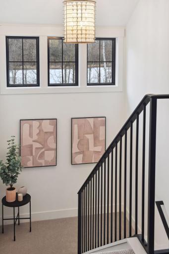 The staircase showcases the homeâs clean lines and thoughtful details, with sleek black railings, crisp white walls, and designer accents that tie the look together.