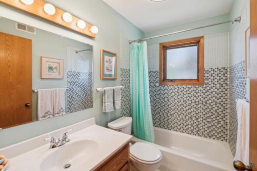 Full bathroom with mosaic tile tub surround and updated fixtures
