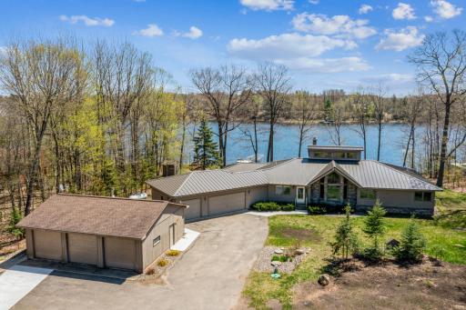 Overhead look at the home, detached garages, and wooded lot with stunning Long Lake shoreline.