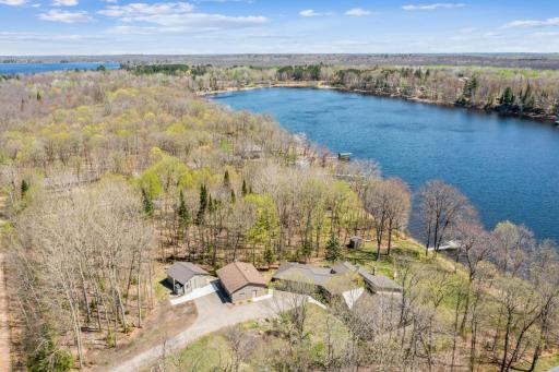 Wide aerial view of Long Lake highlighting the homeâs private lakeshore and wooded surroundings.