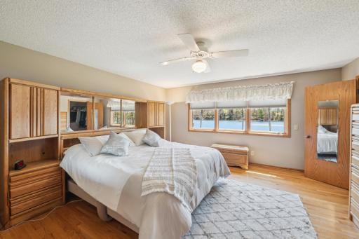 Primary bedroom with hardwood floors, lake-facing windows, and en suite bath access