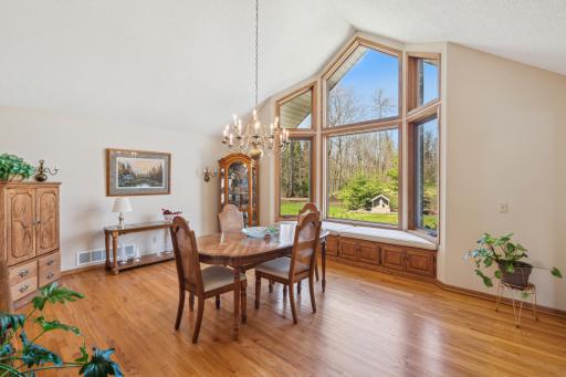 Formal dining space with vaulted ceilings, picture windows, and a charming window seat overlooking the wooded yard.