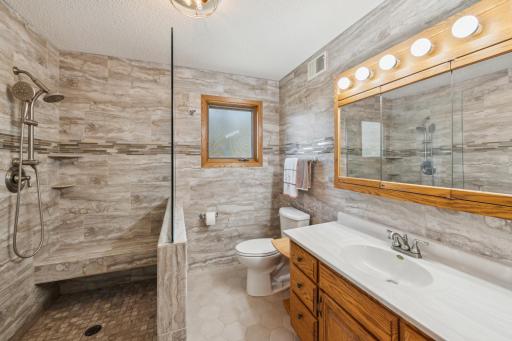 Updated bathroom with walk-in tiled shower, glass divider, large vanity, and modern finishes.