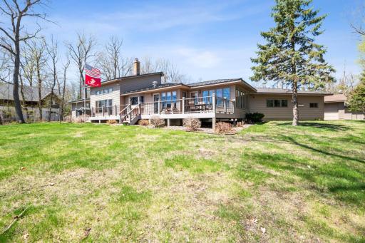 Beautiful lakeside setting with mature trees and professionally landscaped yard surrounding the multi-section deck.