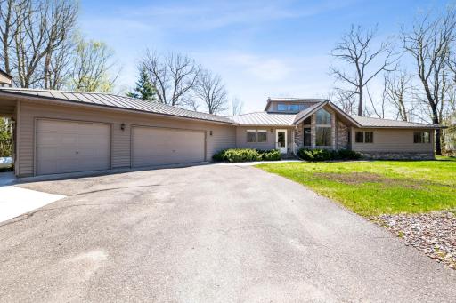 Front view of the attached garage and welcoming entry, with ample parking and lake just beyond the trees.