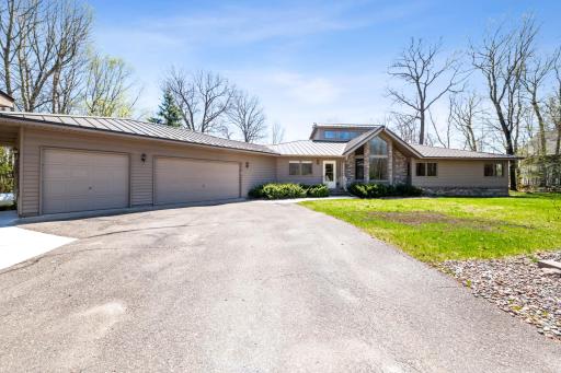 Welcoming front entry with a grand architectural presence, large driveway, and attached garage.