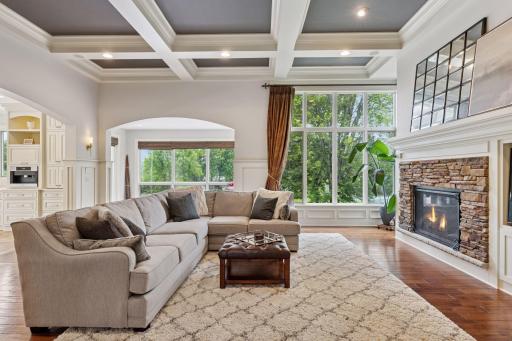 The living room offers volume ceilings with coffered details and overlooks the pool and the lake.