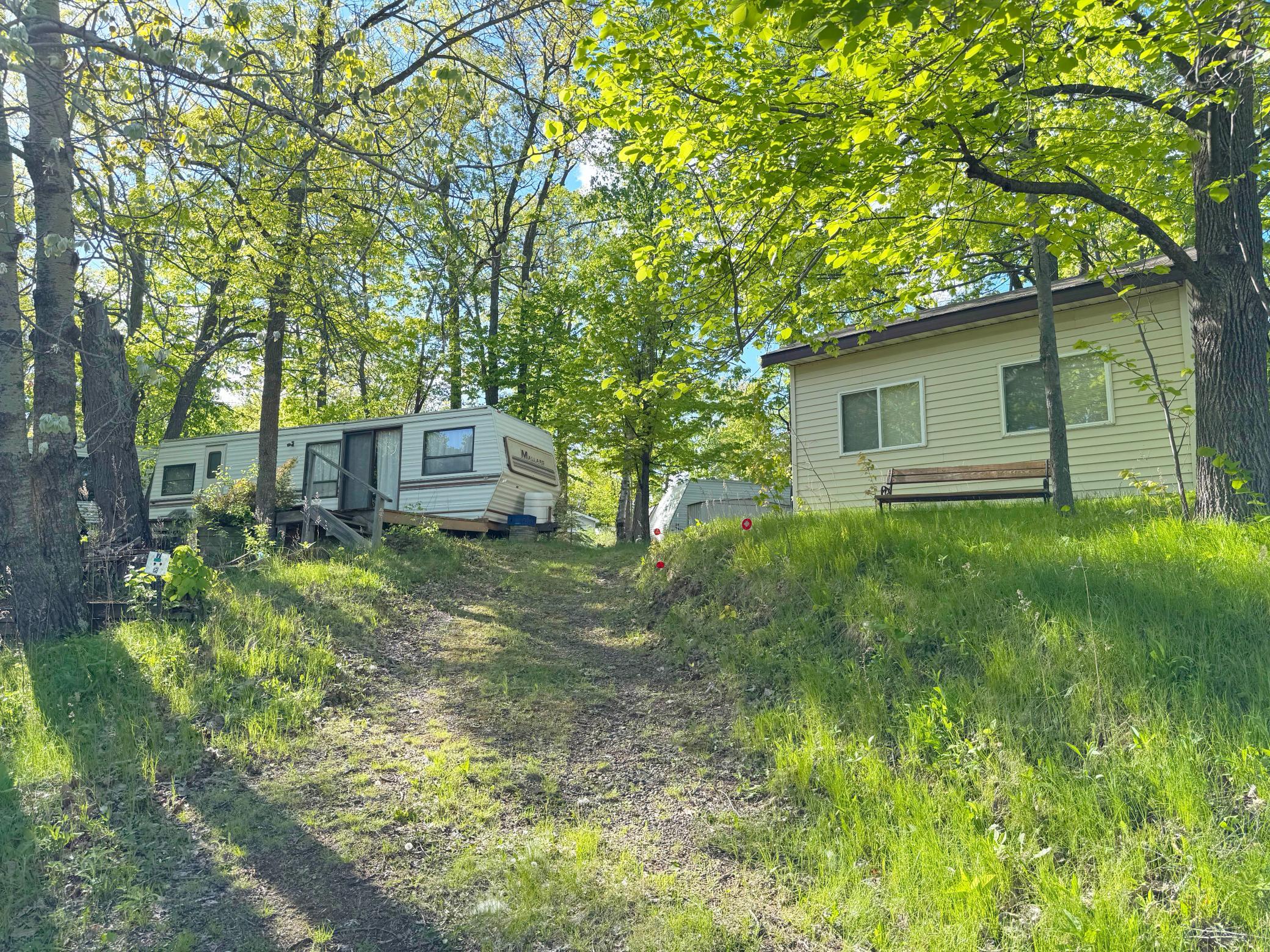 A look at the double lot property from the driveway. Includes a nice MN room, shed and older camper; sold AS-IS