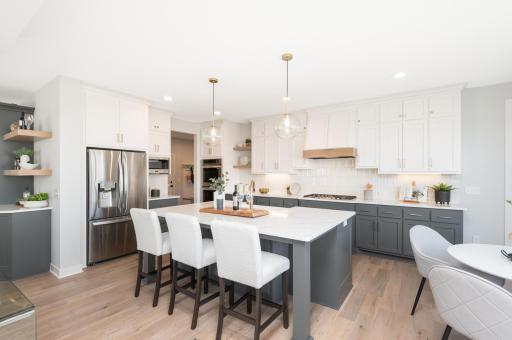 Tastefully done white and gray cabinetry, upgraded appliances, double oven, vented hood and a huge walk in pantry.