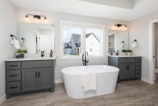 The primary bath with his and hers vanities, quartz counter tops, tile floor and a wonderful, deep soaking tub.