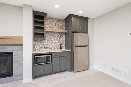 The bar is finished with a cool ceramic back splash, sink, refrigerator and microwave.