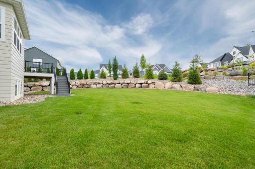 The home owners spared no expense on the this beautiful boulder landscaping, many pines, plants and plush lawn.