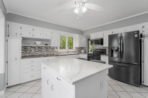 Bright and clean remodeled kitchen with new center island w/ quartz countertop, ceramic floors, and newer appliances.