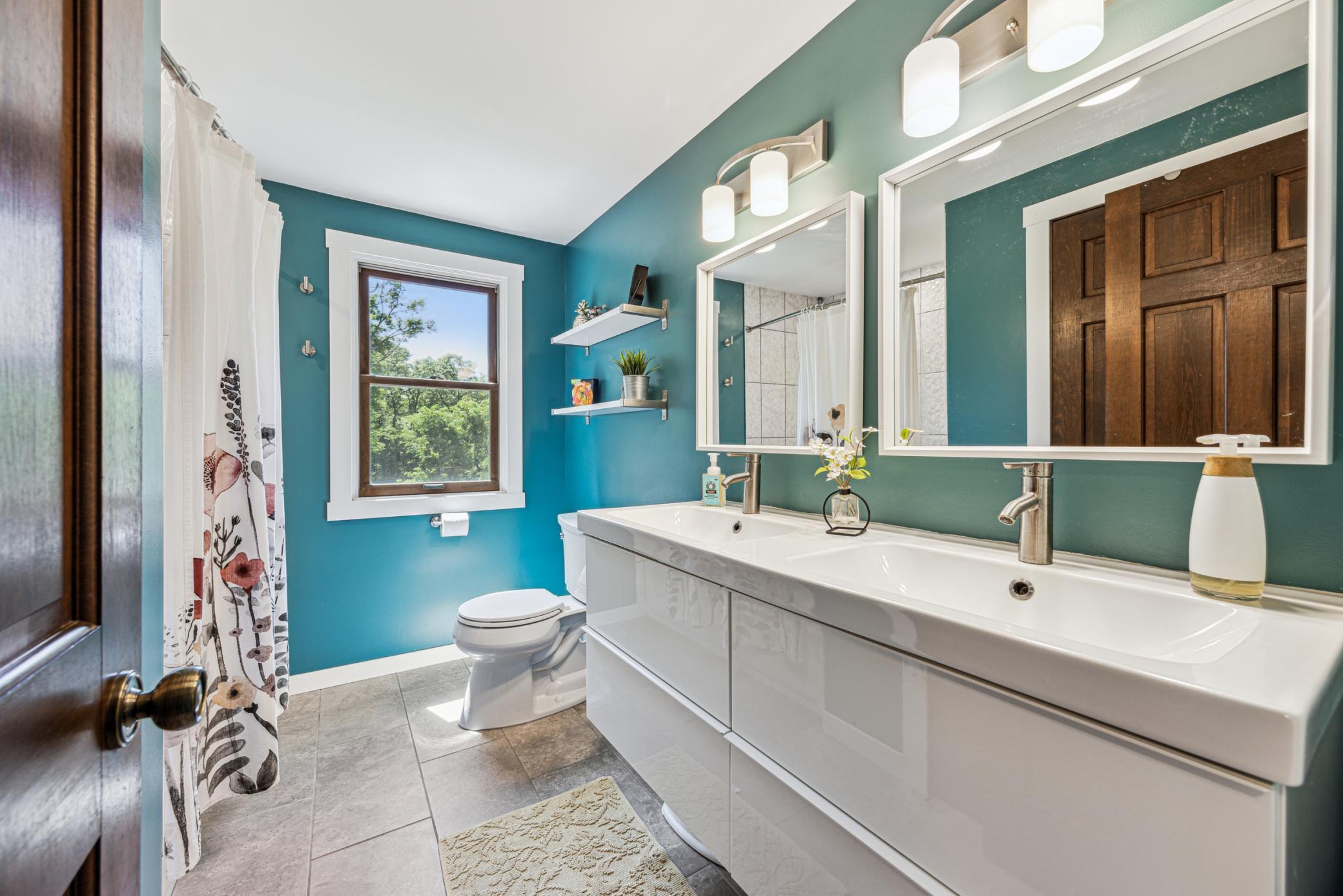 The upper-level bathroom features a modern floating vanity with dual sinks, bright lighting, and plenty of space to get ready each morning.