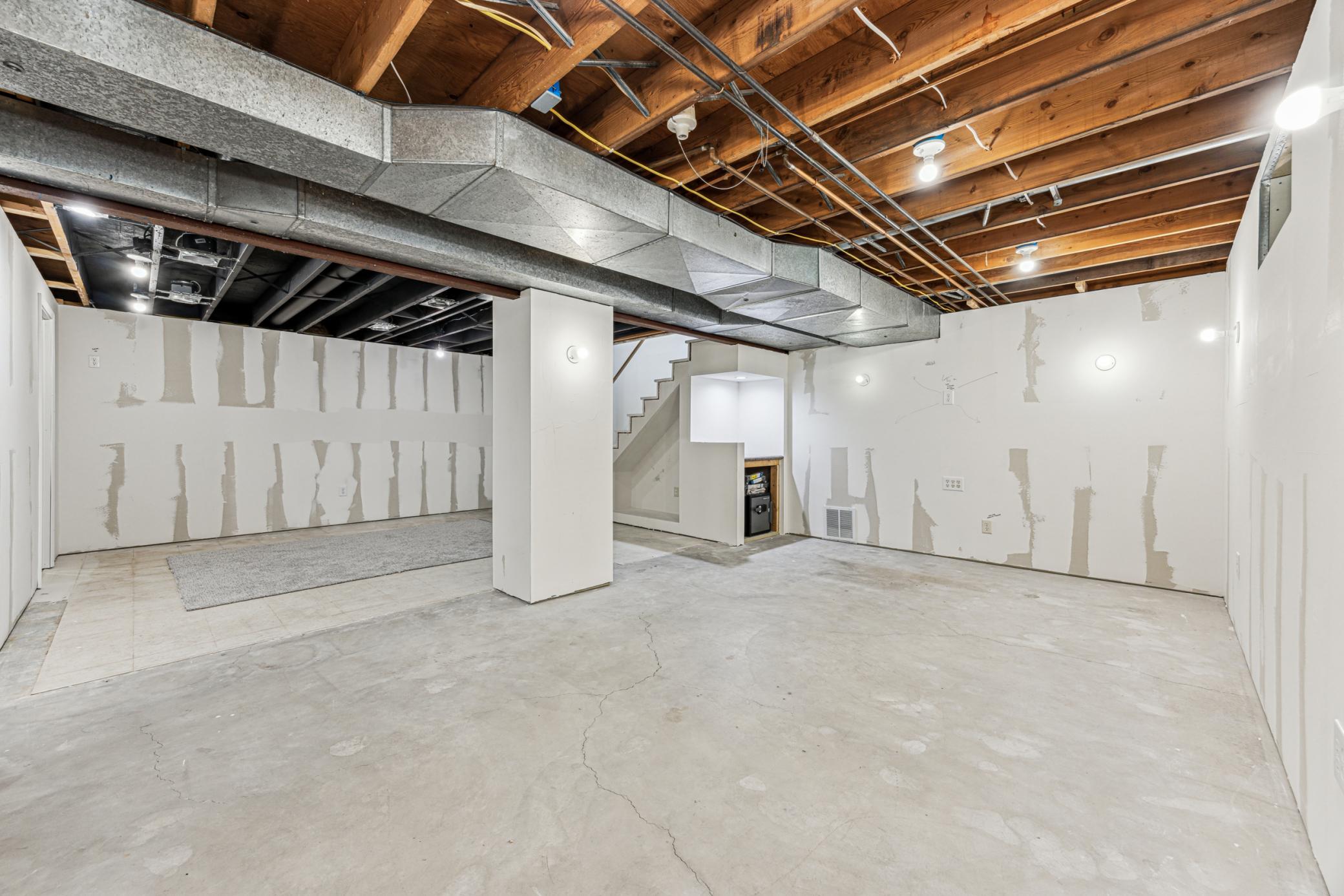The wall lighting was designed for sconce lights, creating a warm and inviting atmosphere. The area beneath the stairs offers endless possibilities, perfect for a custom bar, built-in bookshelf, or a sleek audio/video equipment cabinet.