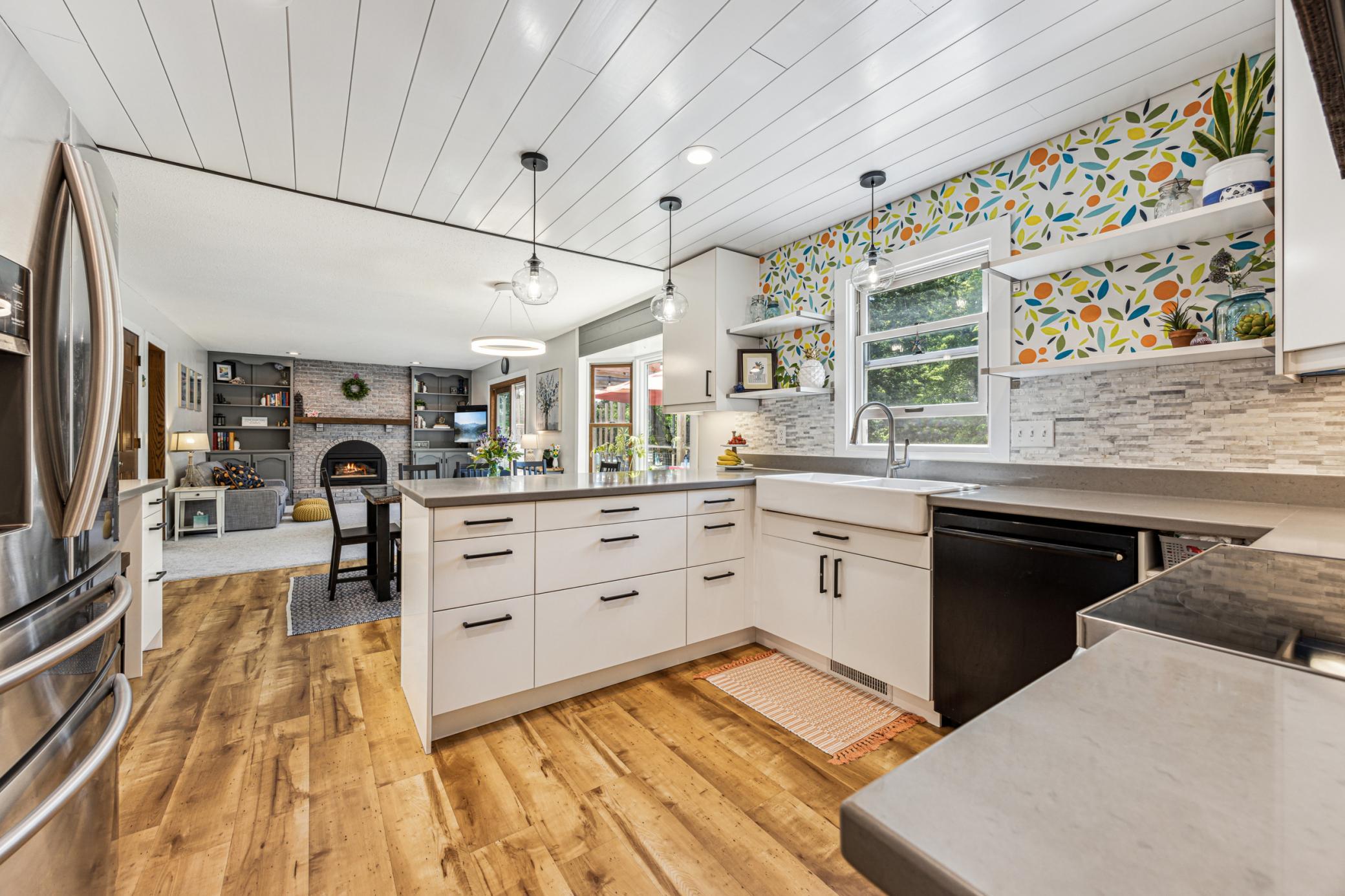 Warm wood-look LVP flooring pairs beautifully with a farmhouse sink, tile backsplash, and easy-to-maintain solid surface countertops.