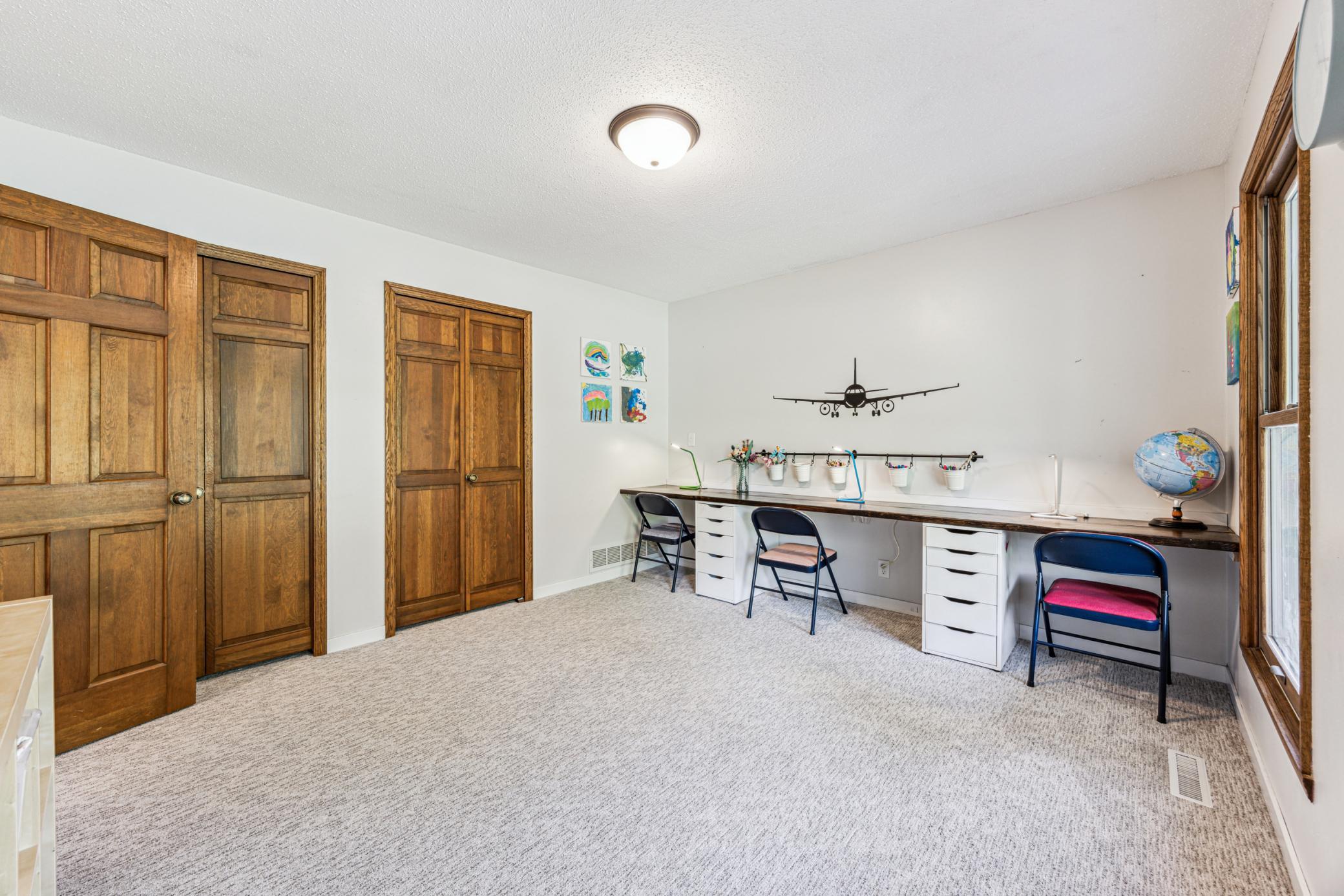 Another look at the main-level bedroom highlights its natural woodwork, dual closets, fresh carpeting, and spacious layout, this is a versatile room that can suit a variety of needs.