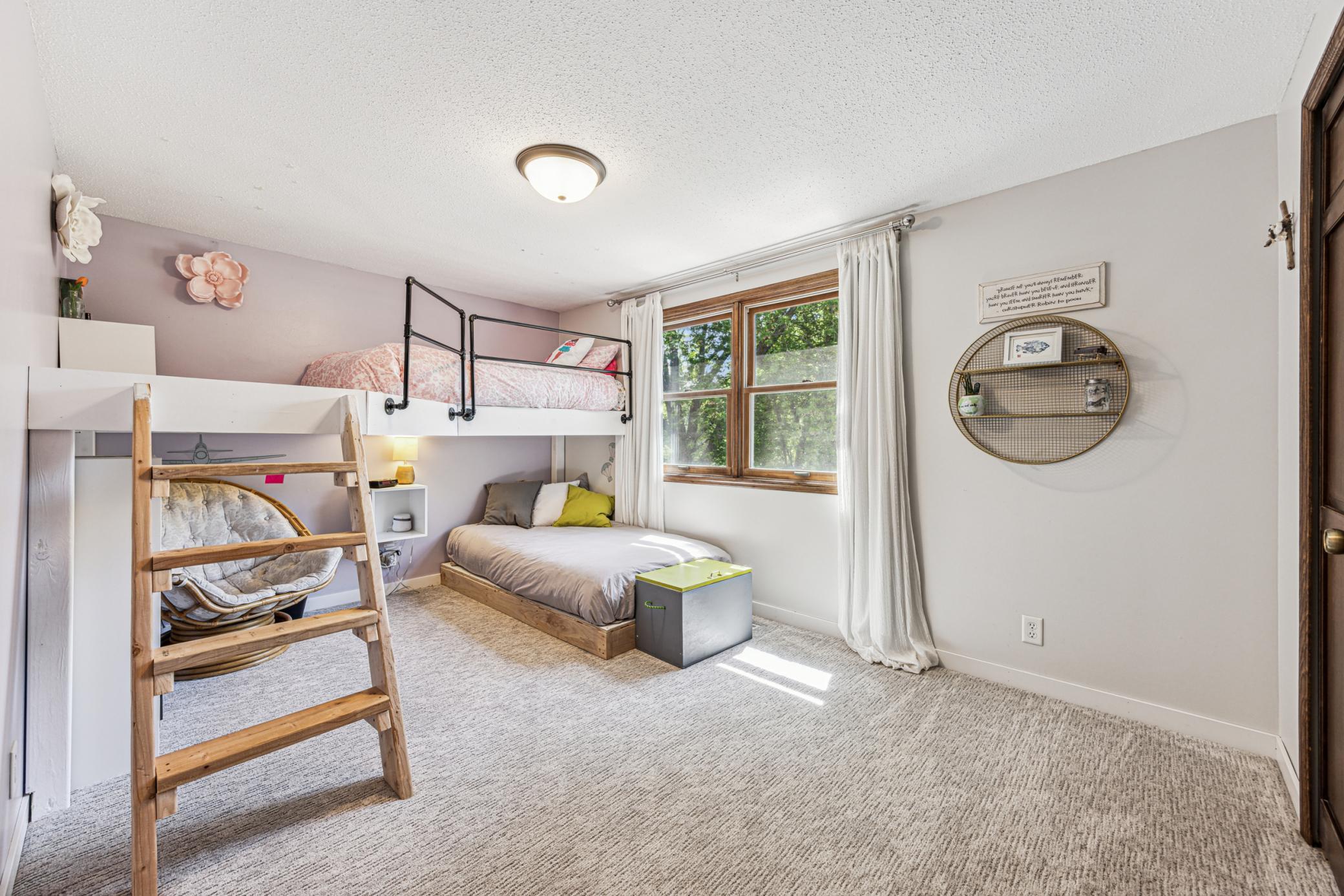 The second upper-level bedroom features fresh carpeting, soothing colors, and a fun built-in bunk bed. With its southern exposure, the room is bright and filled with natural light.