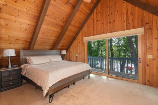 The primary bedroom offers a soaring vaulted ceiling, newer sliding door and deck viewing the lake! Use your imagination here!