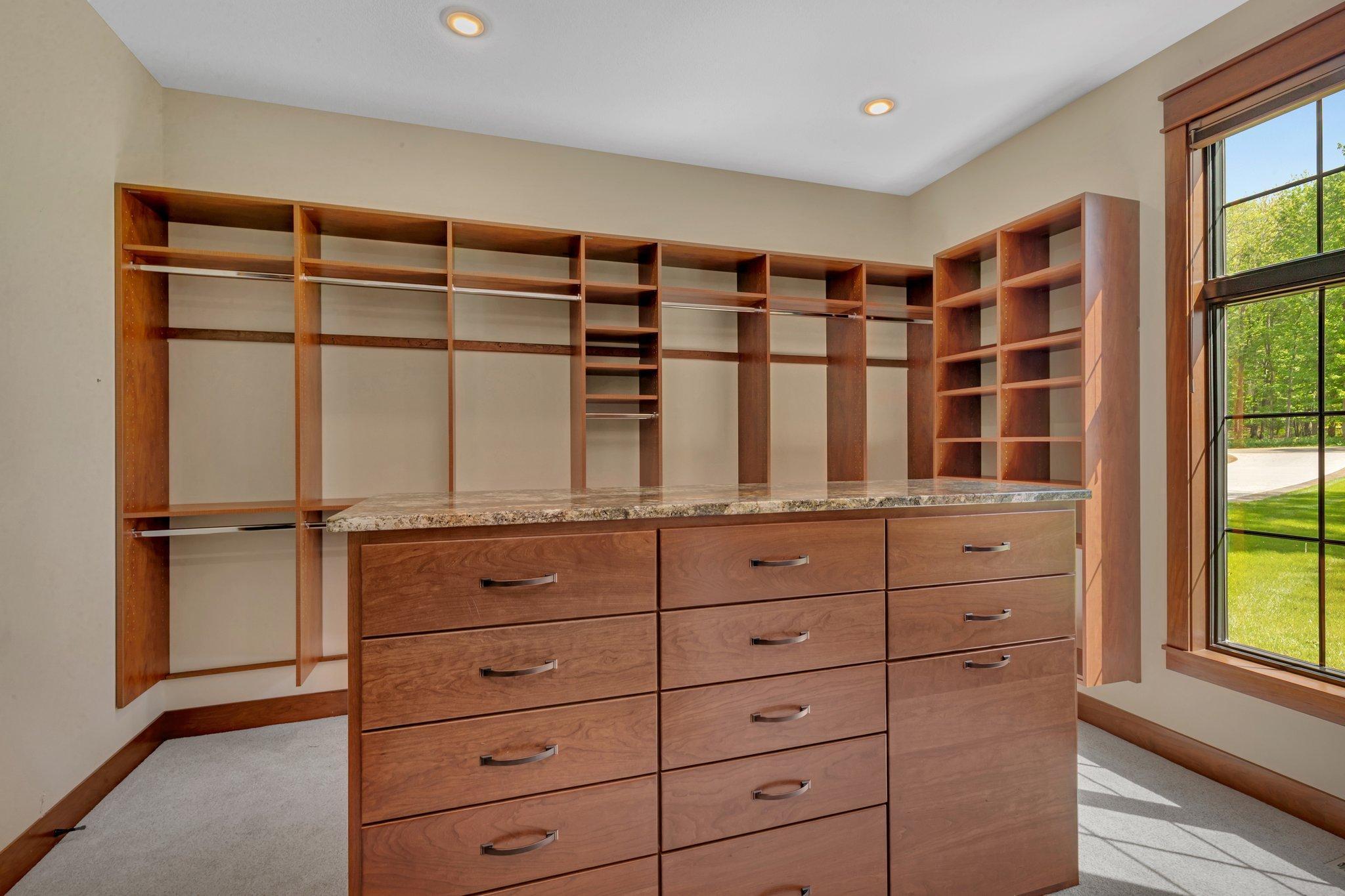 Walk-in closet featuring a central island with built-in drawers, providing stylish storage and easy organization.