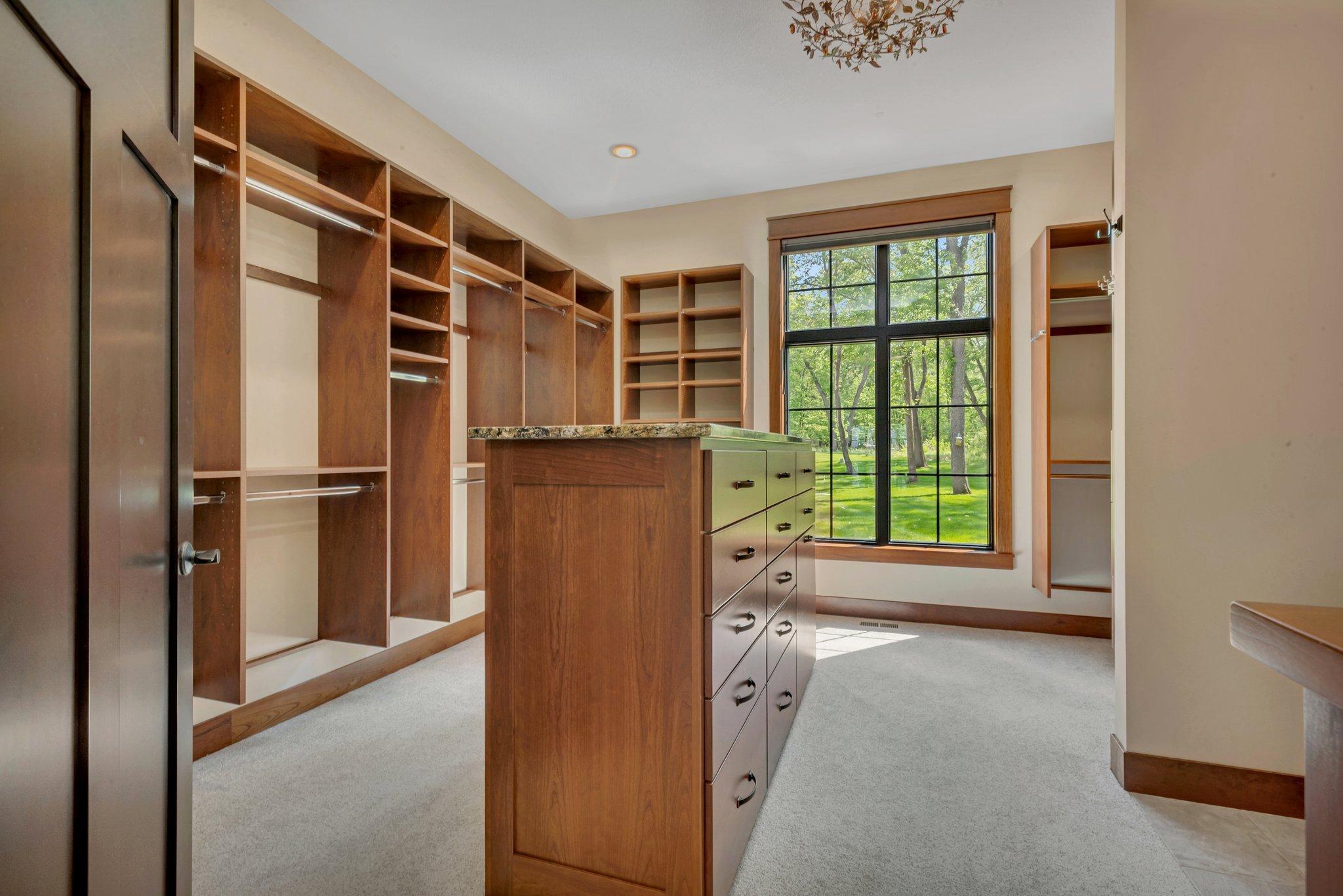 Walk-in closet featuring a central island with built-in drawers, providing stylish storage and easy organization.