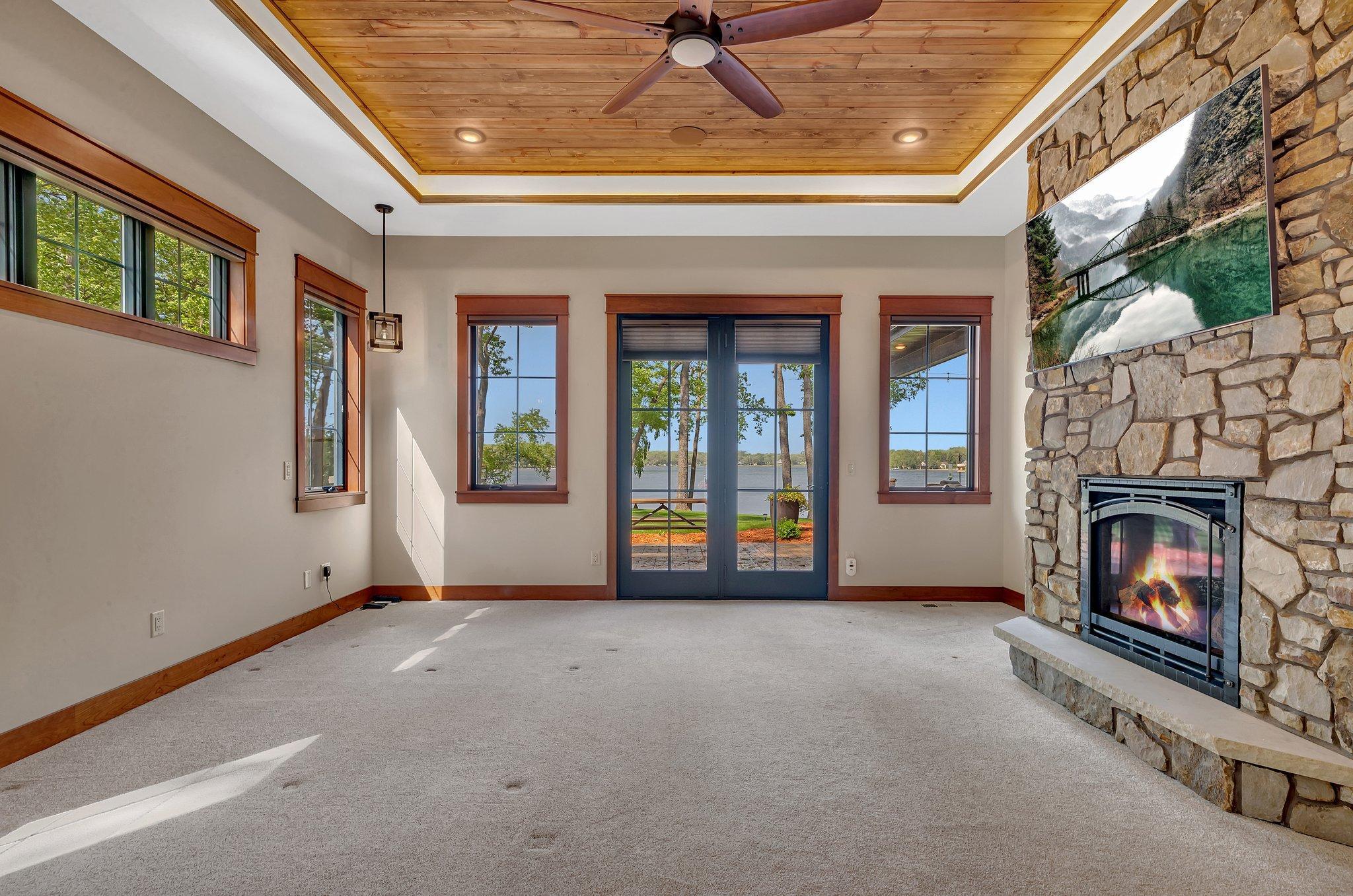 The Primary bedroom with its large floor-to-ceiling windows frame a breathtaking view of the lake and a stone fireplace will add ambience.