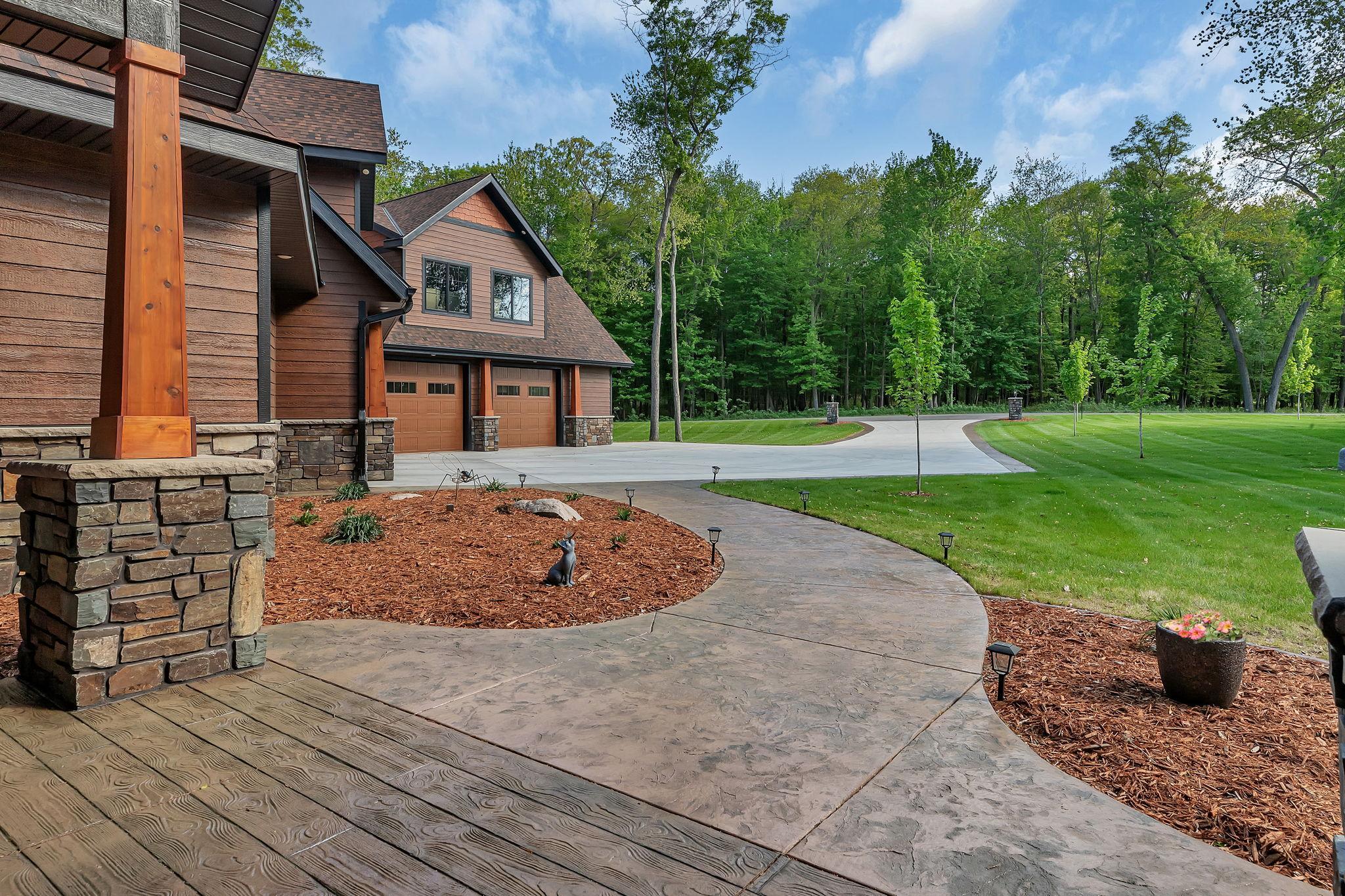 Beautifully landscaped front yard featuring a stamped concrete walkway and a durable concrete driveway, offering great curb appeal and a welcoming entrance.