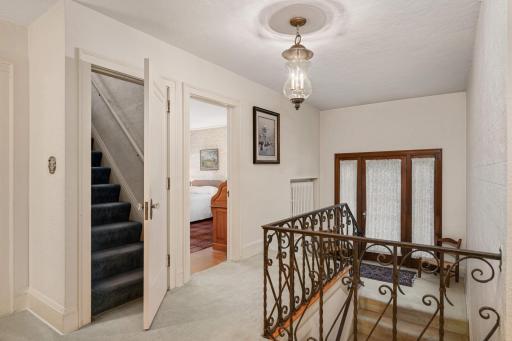 The staircase landing has windows and a leaded glass door to a balcony