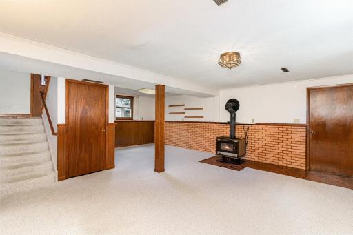 Another view of the large living room area. There is a half wall of exposed brick and tile around the wood burning stove in the family room.