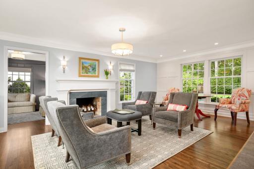 The gracious living room features a classic wood-burning fireplace with a soapstone surround, sconces, a âpaneled feature wall,â crown molding and six double-hung windows