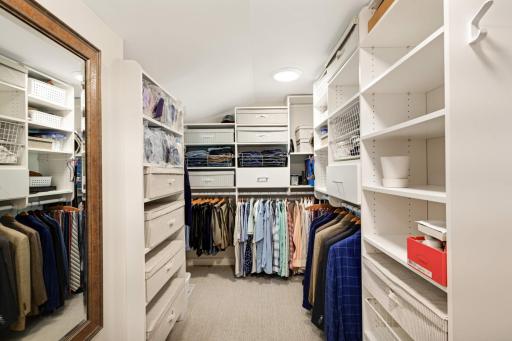 A large walk-in closet with custom organizers and a window.