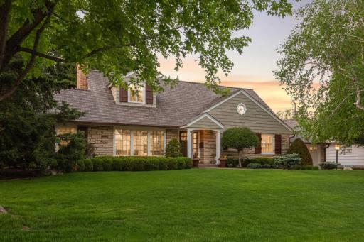 The stunning home has wonderful curb appeal with its stone and cedar shingle exterior, wood shutters, cedar shingle roof, copper gutters, and beautiful landscaping