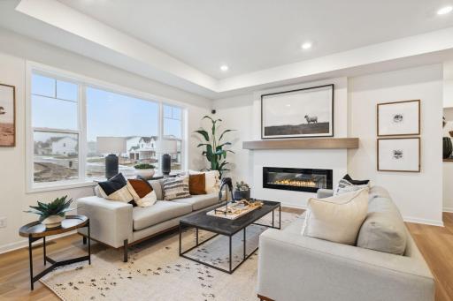 Sun-soaked living room with expansive windows, sleek gas fireplace, and open layout - perfect for cozy nights or stylish entertainment.
